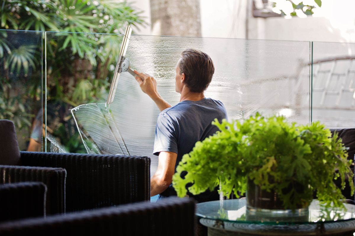 A man cleaning glass on a patio, using a cloth to wipe down the surface for a clear view.