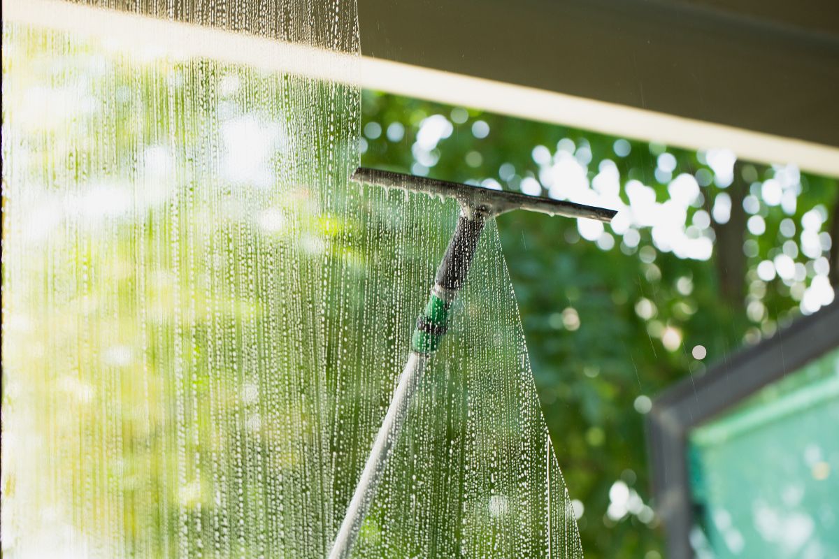 A window with a hose and a window cleaner, showcasing the process of window cleaning in Bedford.