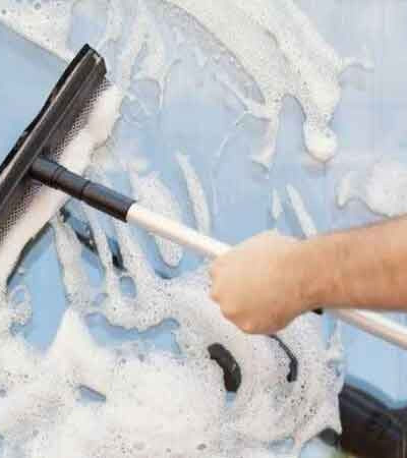 Individual cleaning a car with a foam brush, representing the expertise of Atrium Window Cleaning.